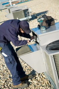 commercial-HVAC-technician-works-on-rooftop-AC-unit